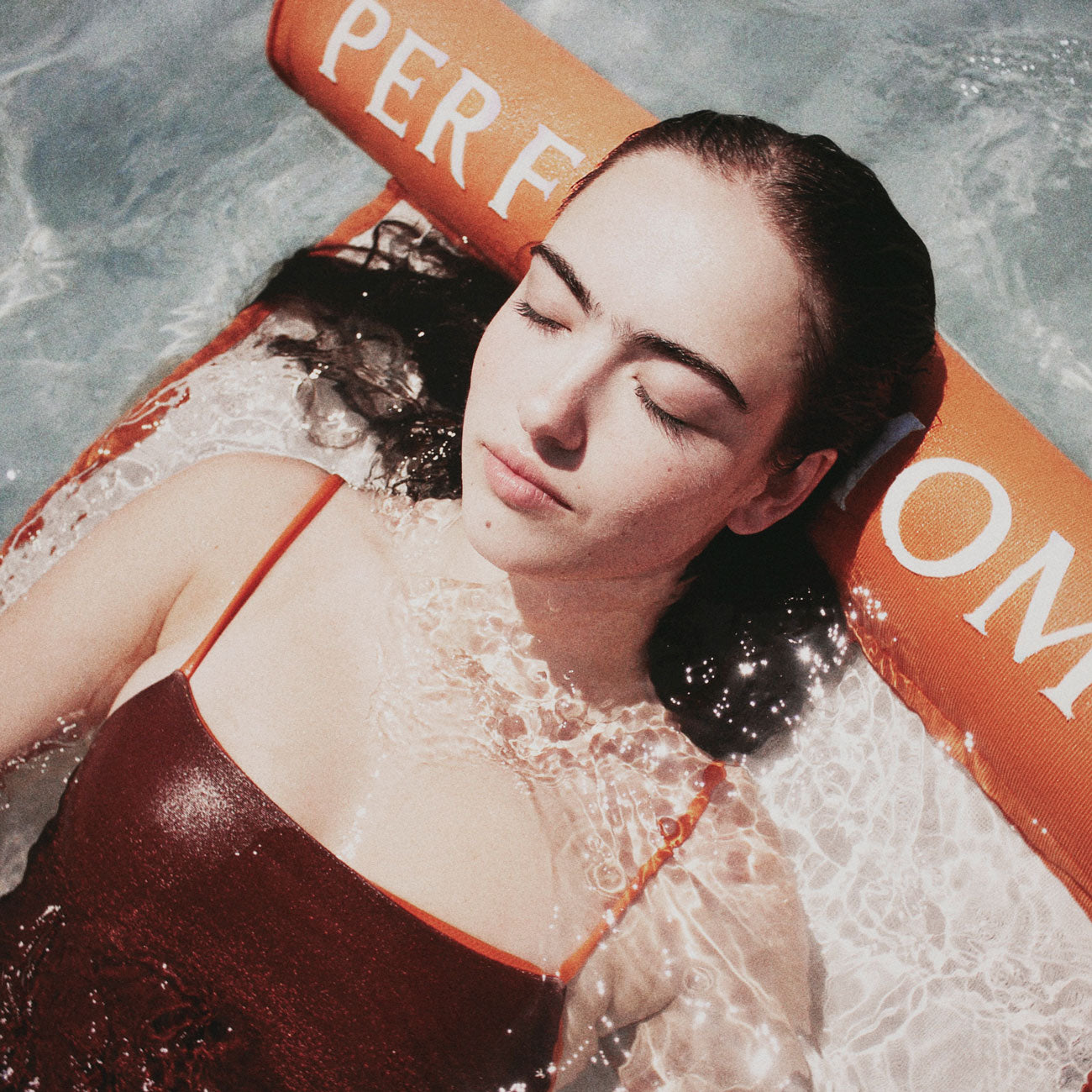 The relaxed face of a women in a luxury pool float hammock.