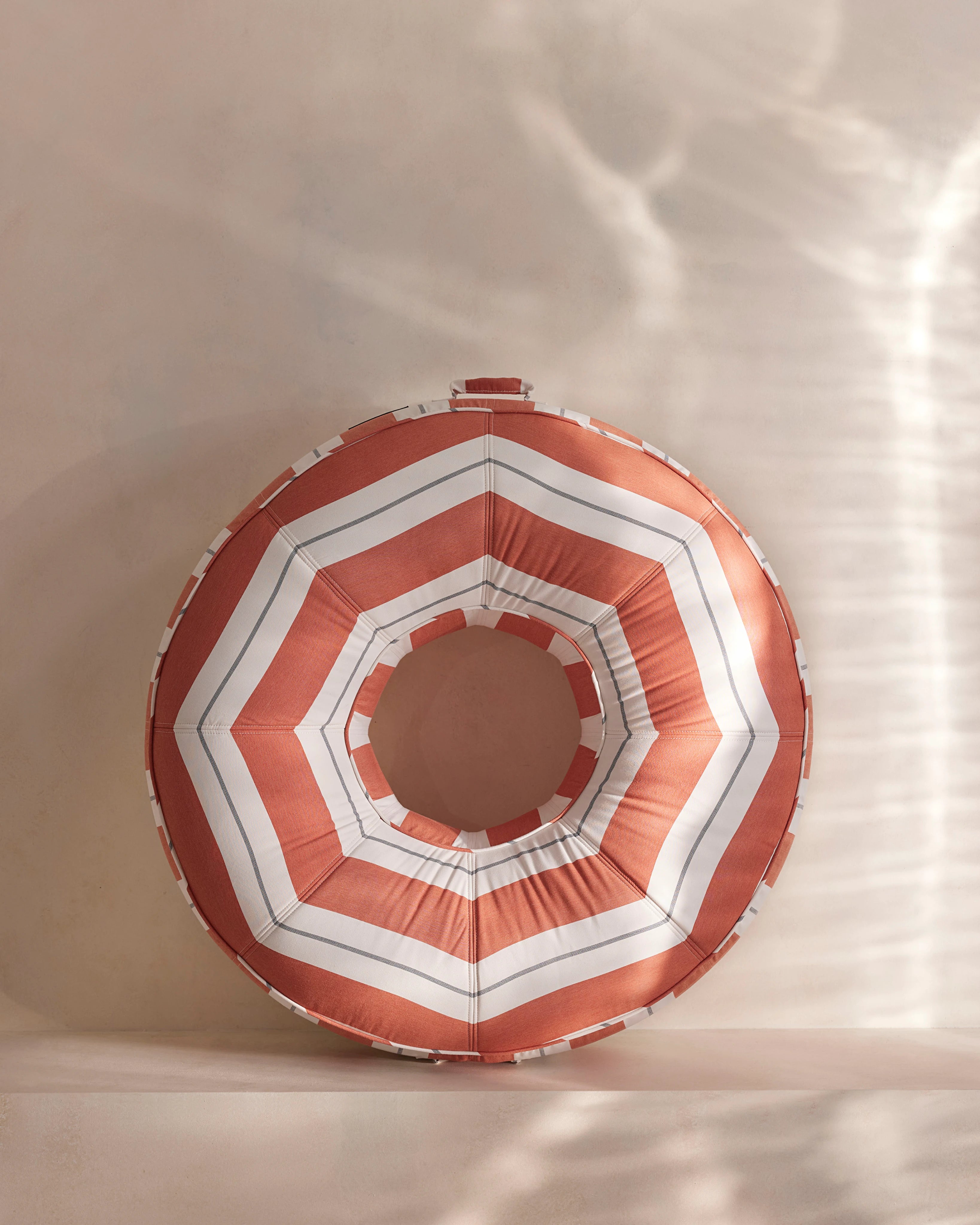 Round luxury pool float with bold orange and white chevron stripes, designed for adults — a high-end pool accessory from Oliver James Lilos for elegant relaxation.