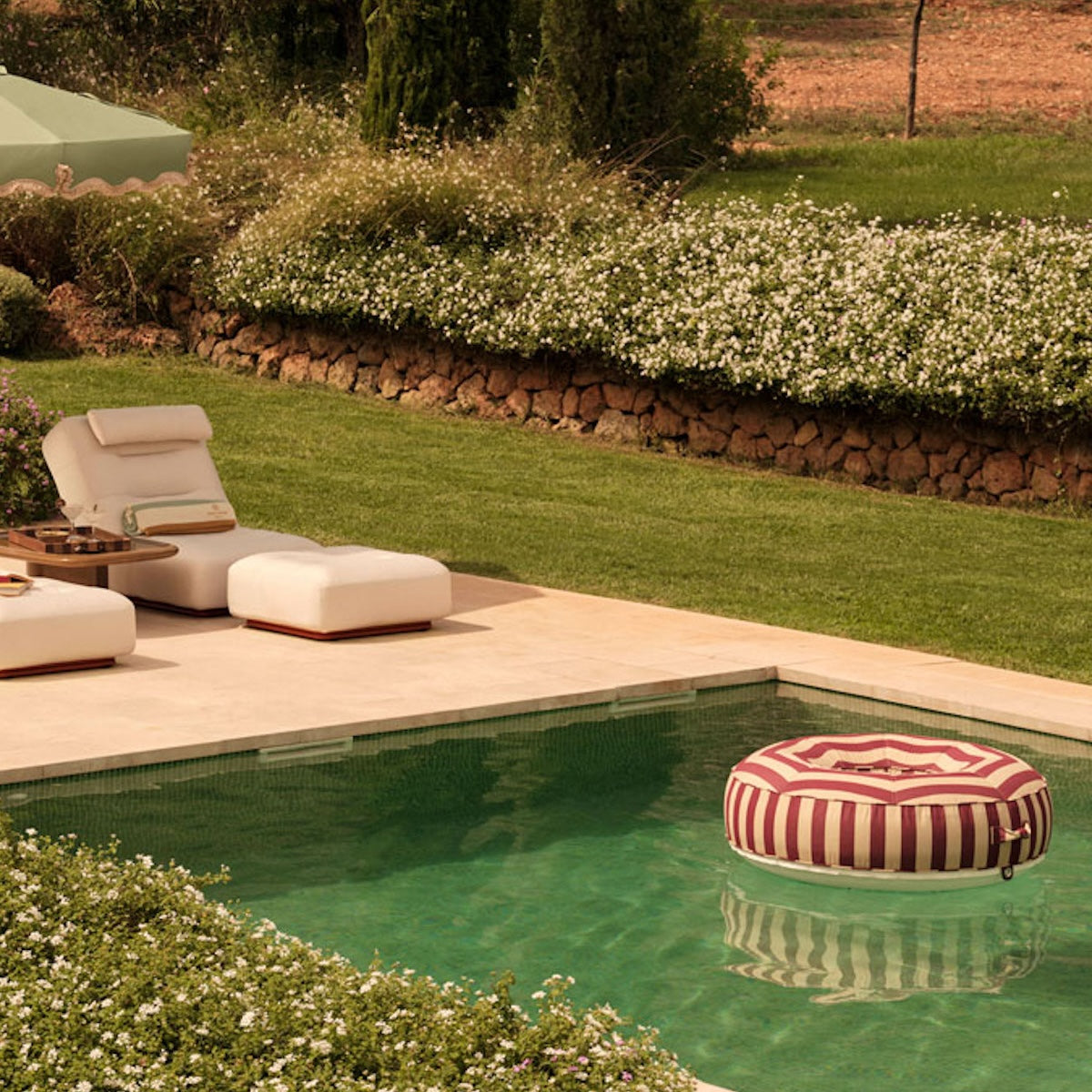 A red and beige luxury pool float ring floating in a swimming pool.
