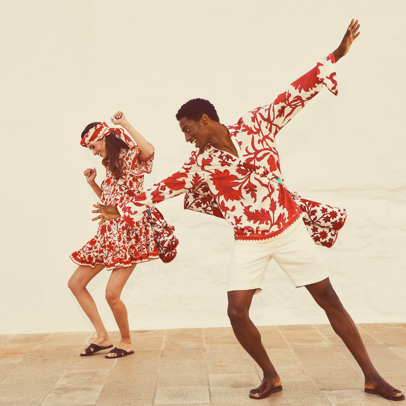 A man and a woman holding two luxury pool floats upholstered in red and white fabric.