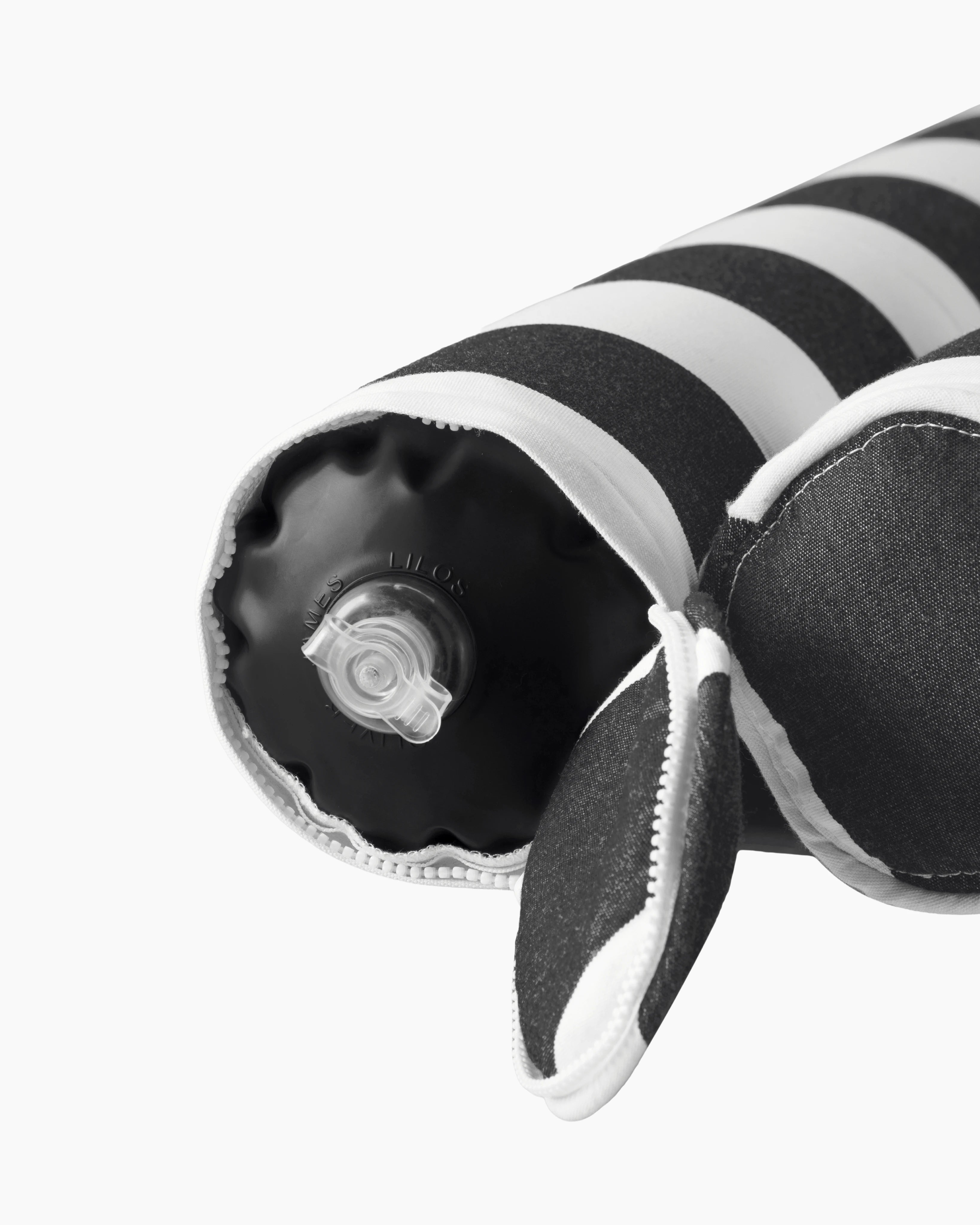 Close-up of the air valve on the end of a striped inflatable bolster, discreetly hidden by a zippered sleeve — refined design meets functional elegance.