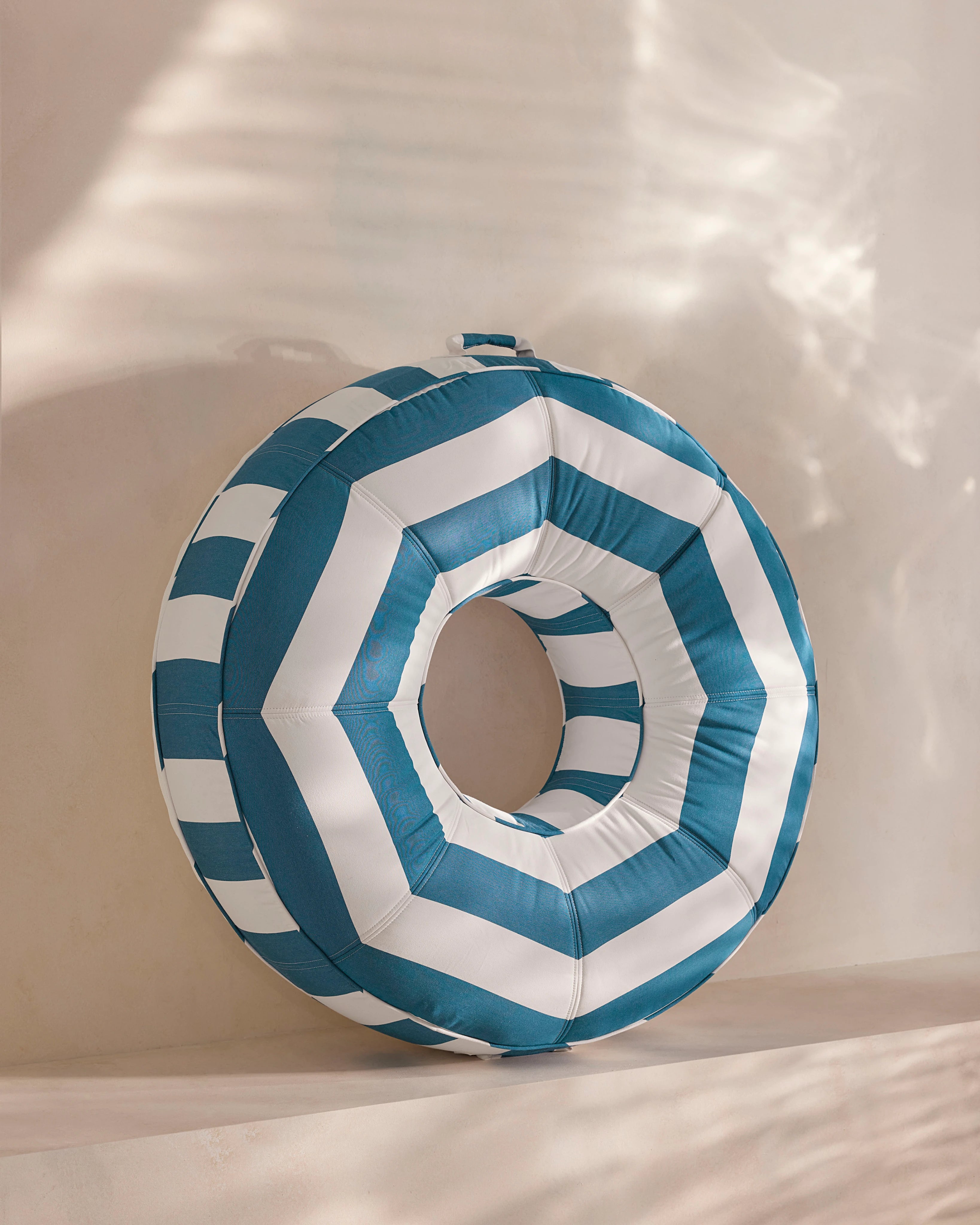 Round luxury pool float with bold blue and white chevron stripes, designed for adults — a high-end pool accessory from Oliver James Lilos for elegant relaxation.