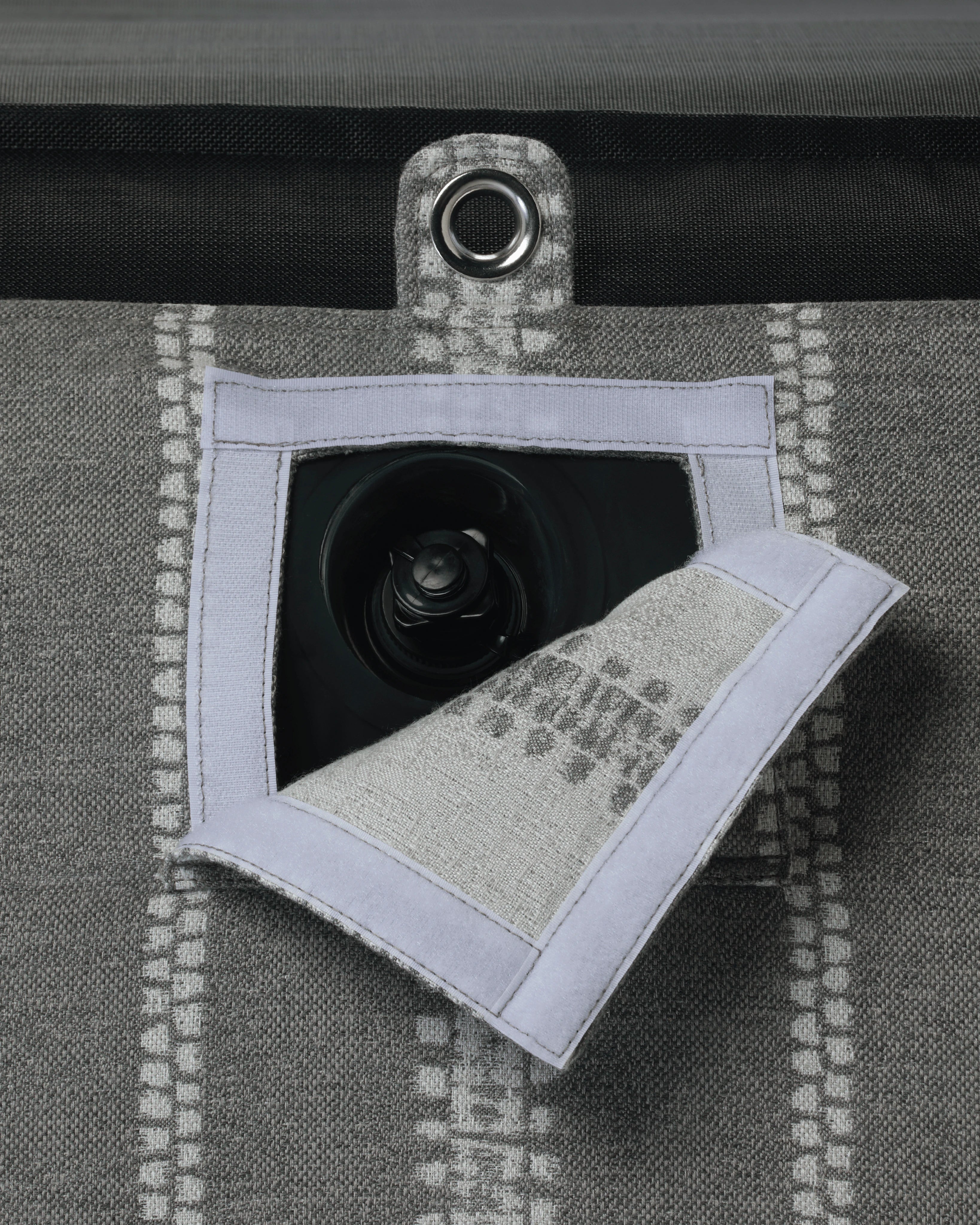 Close-up of concealed inflation valve beneath a neatly stitched flap in grey and white striped jacquard fabric, highlighting discreet functional design.