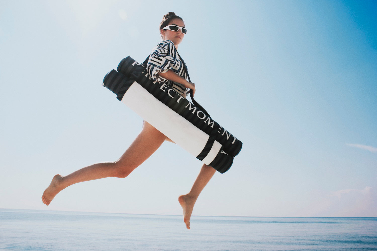 A women jumping with a blue denim luxury pool float hammock.