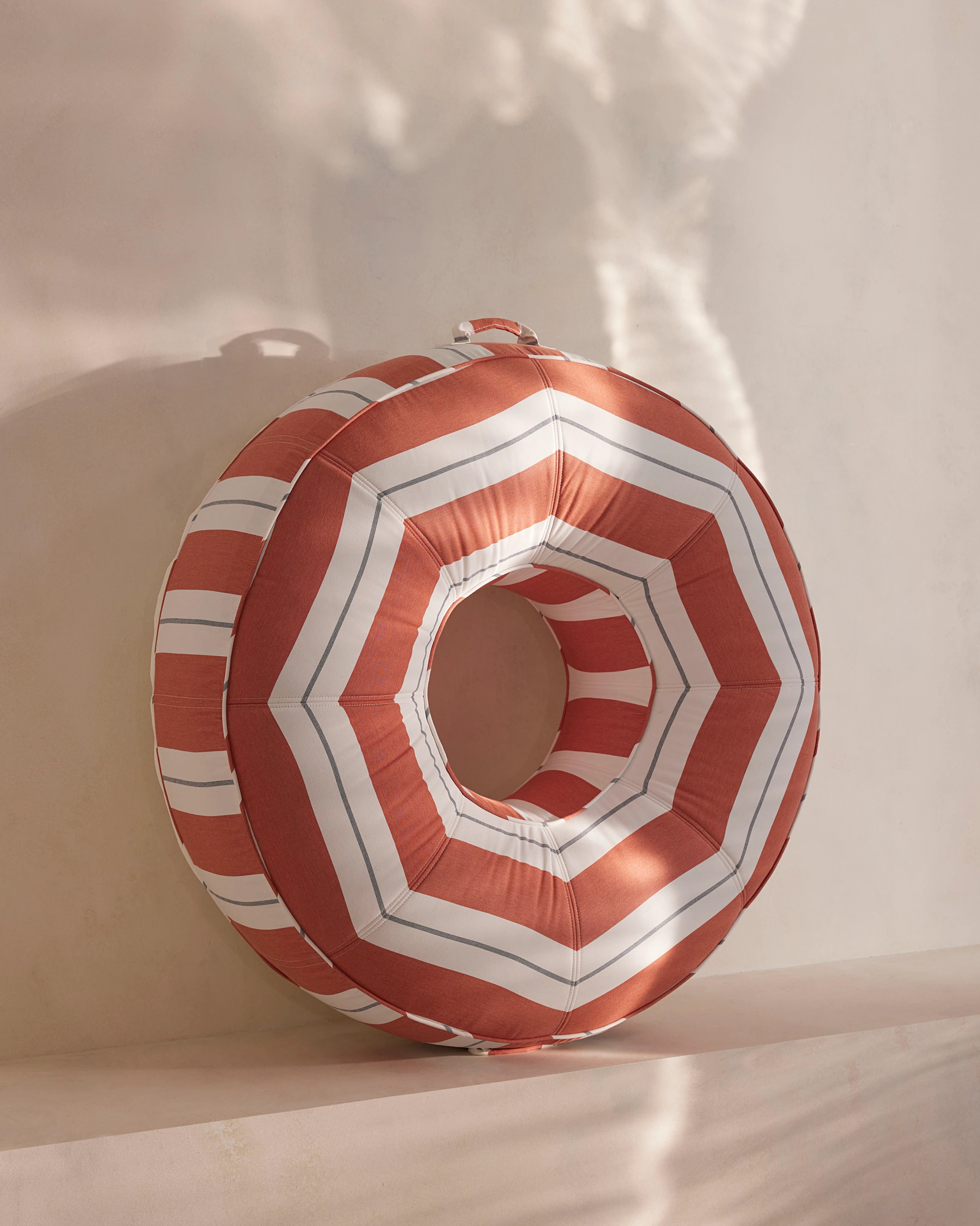 Round luxury pool float with bold orange and white chevron stripes, designed for adults — a high-end pool accessory from Oliver James Lilos for elegant relaxation.