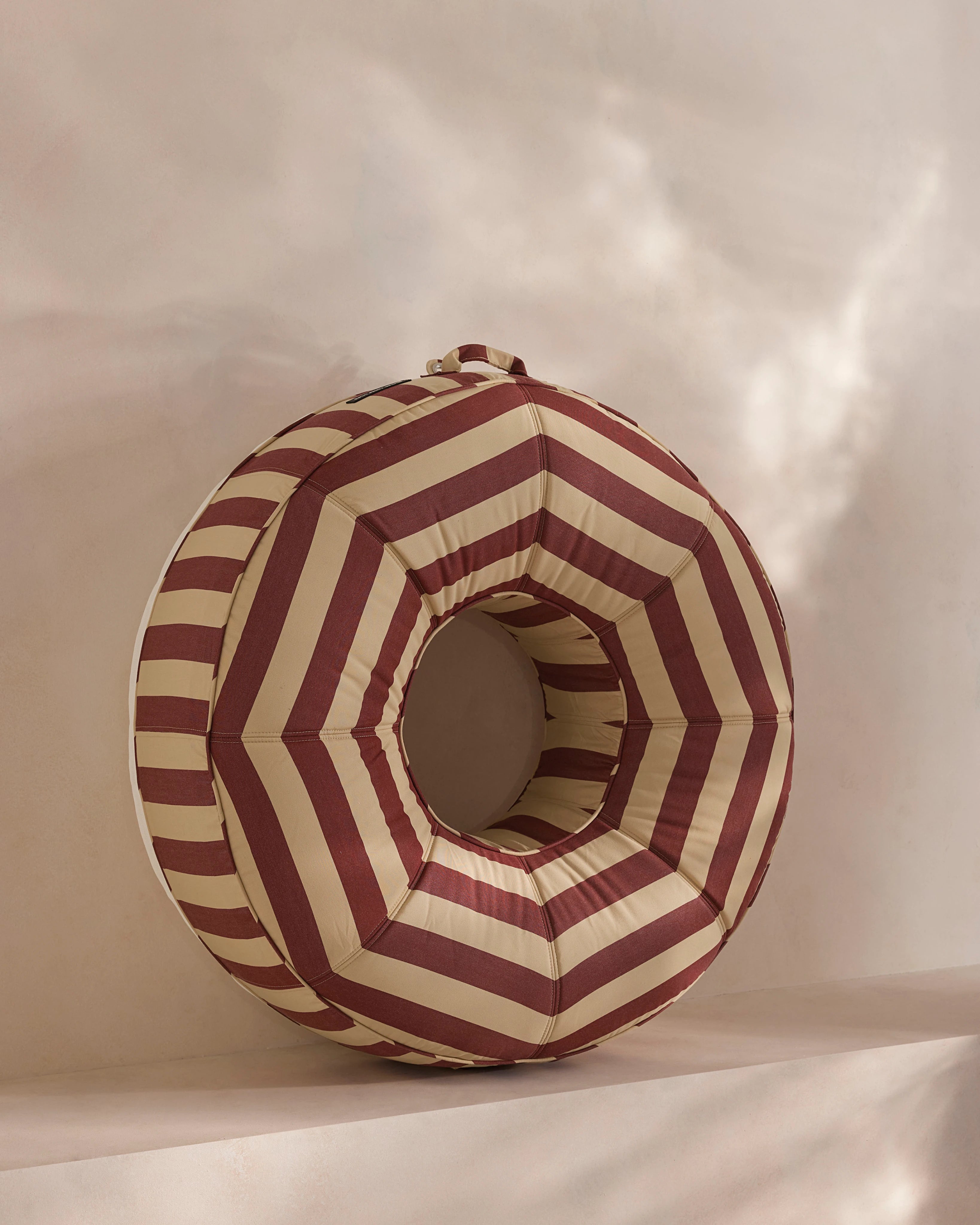 Round luxury pool float with bold red and beige chevron stripes, designed for adults — a high-end pool accessory from Oliver James Lilos for elegant relaxation.