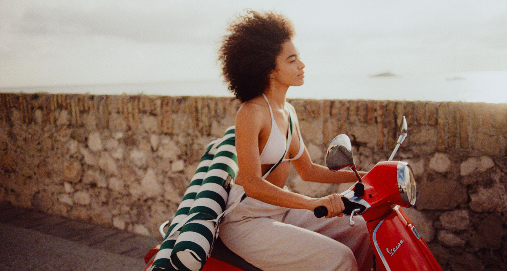 A women riding a red vespa with a luxury pool float on her back