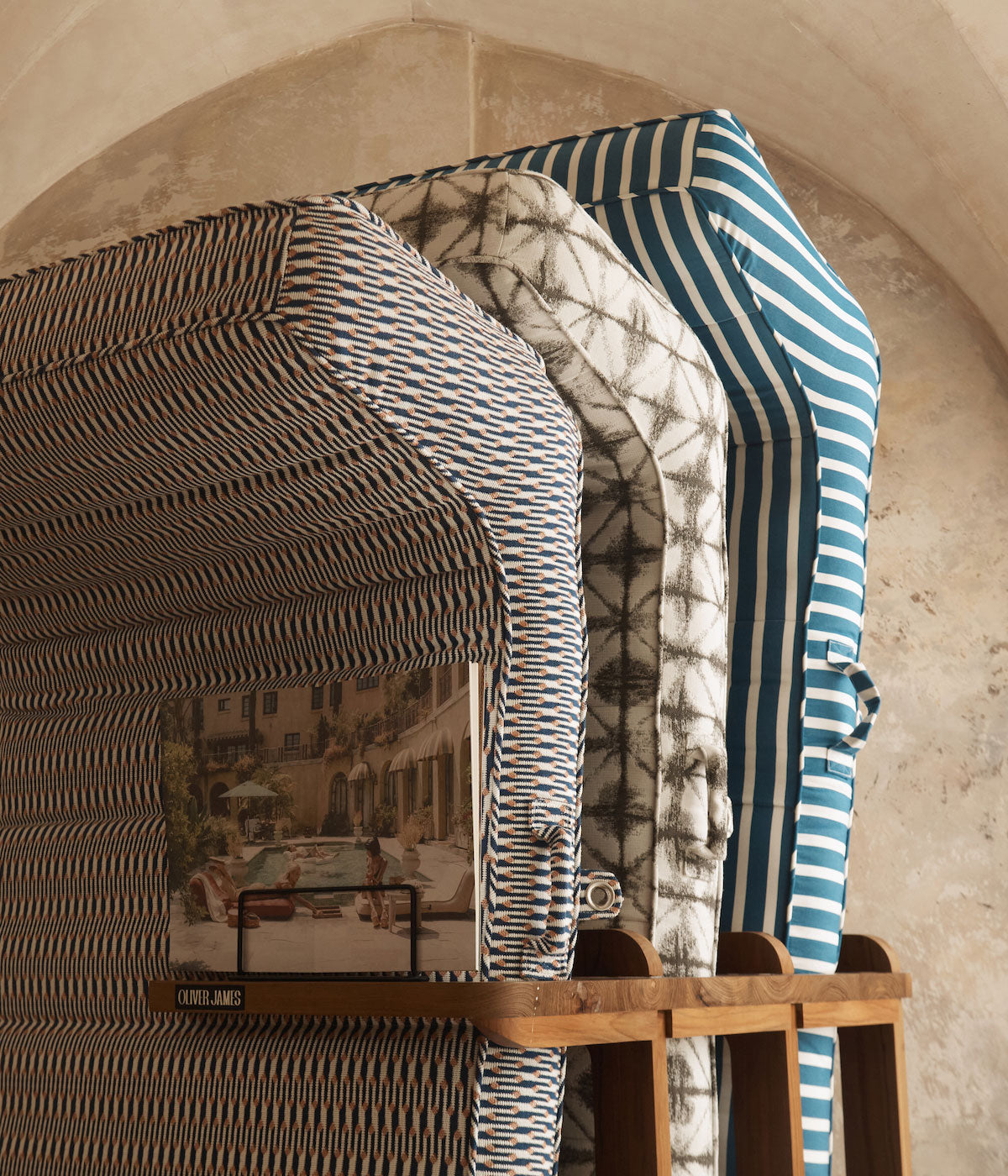 Three luxury pool floats stacked using a teak wooden rack in a old marble stone walled archway.