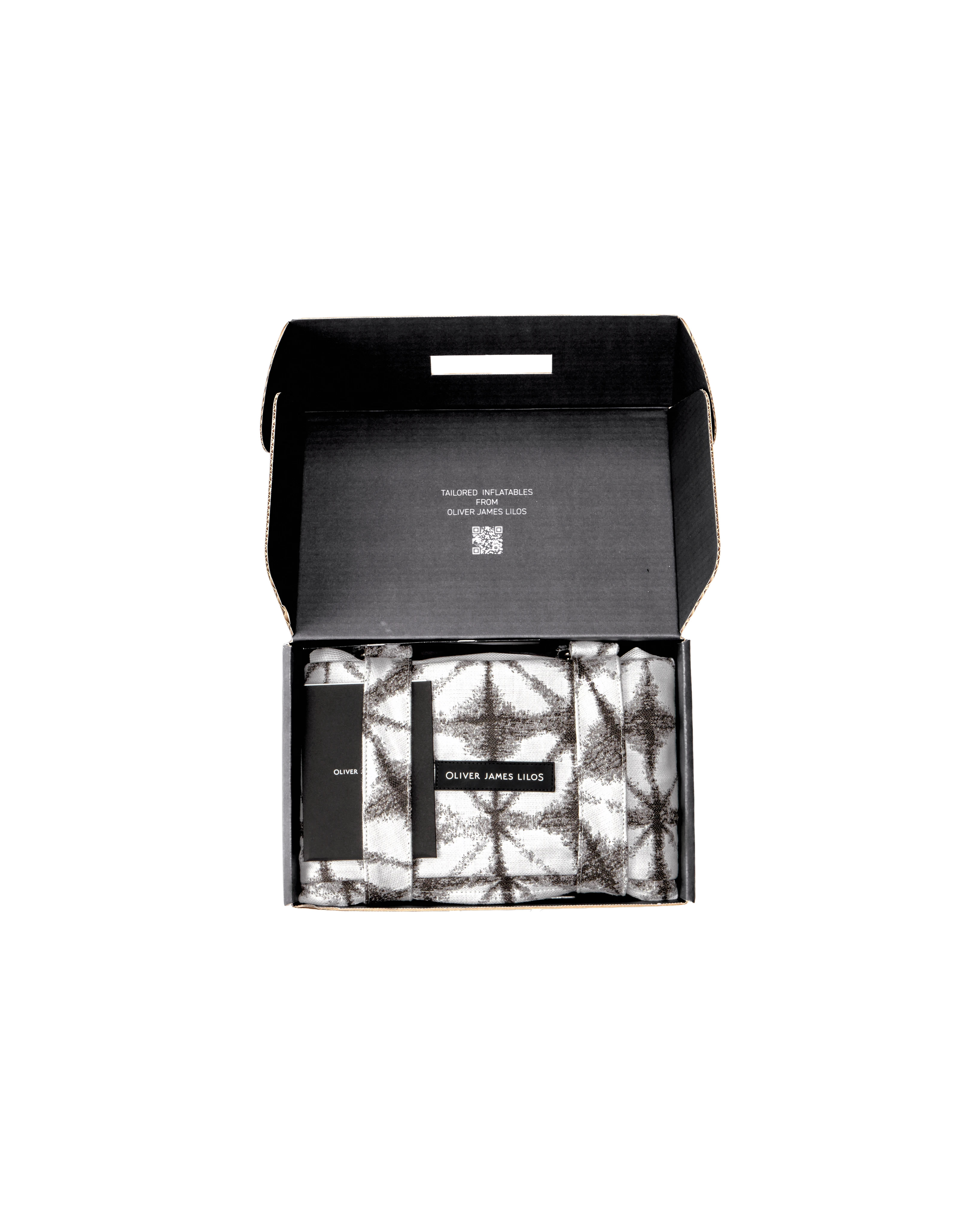 Oliver James floating hammock packed inside a sleek black box, with folded grey and white geometric jacquard fabric bolsters and branded tag — a premium pool float presented with care.